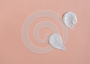 White smear of cosmetic cream on a beige background. Creamy foundation texture isolated. Smear of face cream. Close up