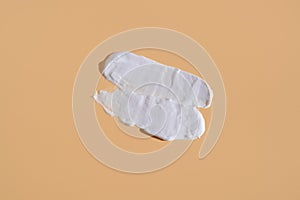 White smear of cosmetic cream on a beige background. Creamy foundation texture isolated. Smear of face cream. Close up