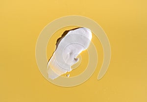 White smear of cosmetic cream on a yellow background. Creamy base texture isolated. A smear of face cream. Close-up of