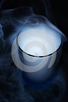 White smoke on black fabric background in glass. Smoke spreads over the background. Vaping culture, life without cigarettes.