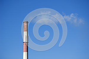 White smoke from the boiler room chimney against the blue sky.