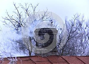 White smoke from the chimney of an old house during frost