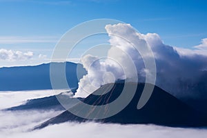 White smoke coming out of volcanoes surrounded by white clouds of mist.