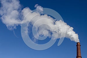 White smoke from the factory brick chimney. Blue sky. Ecology and production. Copy space