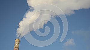 White smoke from factory chimneys rising into the blue sky, power generation and air pollution and atmosphere.