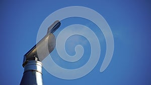 White smoke flies from Stainless Steel Wind Directional Cowl on Chimney Rotating Gently on Wind. Flue pipe for the stove