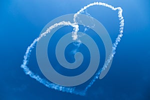 White smoke heart in blue sky.