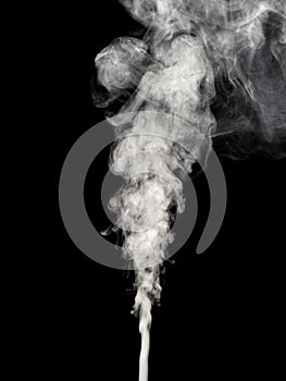 White smoke isolated on a black, swirls and rises upwards as an abstract effect