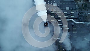 White smoke streaming out of a large industrial smoke stack at a factory.