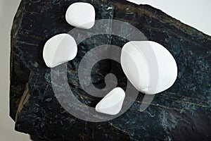 white smooth stones laying over one black flat stone