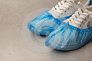 White sneakers in boot covers on a grey background. Minimalism