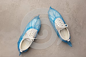 White sneakers in boot covers on a grey background. Top view. Minimalism