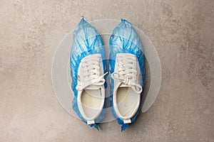 White sneakers in boot covers on a grey background. Top view. Minimalism