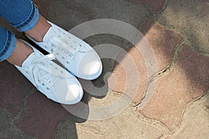 White sneakers on girl legs in blue jeans