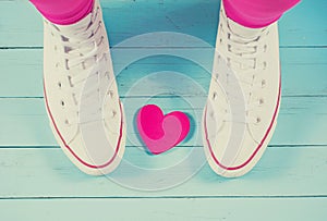 White sneakers with heart on blue wood background, filtered
