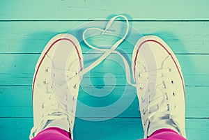 White sneakers with heart on blue wood background, filtered