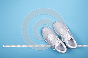 White sneakers with measuring tape on blue background.