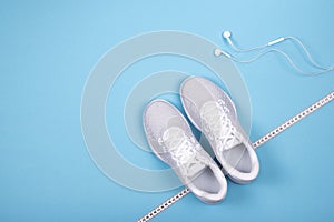 White sneakers with measuring tape and earphones headphones non blue background. n