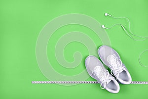 White sneakers with measuring tape and earphones headphones  non blue background. n
