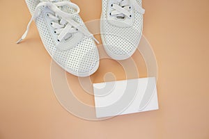 White sneakers with a melamine sponge on a beige background