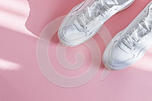 White sneakers on a pink background.