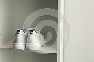 White sneakers on a white closet shelf.
