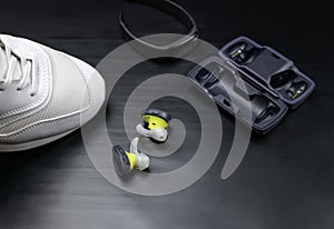 White sneakers, wireless headphones with opened case and fitness tracker.  Fitness concept.