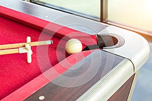 White snooker ball and cue stick with rest near the corner hole