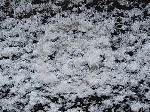 White snow on a black metal surface. Abstract winter grunge background.