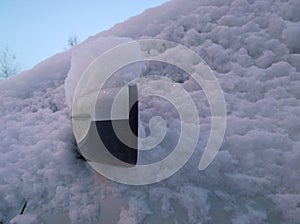 White snow covered dirty side mirror of car. Winter background. Frost, blizzard and snowfall. Protection of vehicle against corros