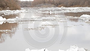 White snow-covered ice floes float along the wide river. Ice drift in the fog at dawn. Winter in Europe.