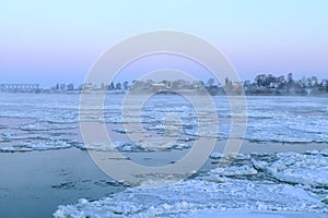 White snow-covered ice floes float along the wide river Neman