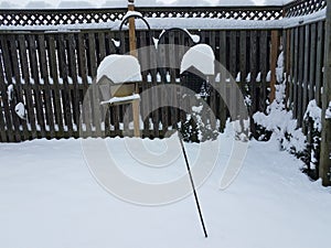 White snow on wood fence and bird feeders