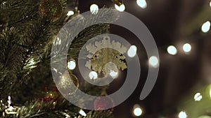 White snowflake on christmas tree against bokeh lights in home at night