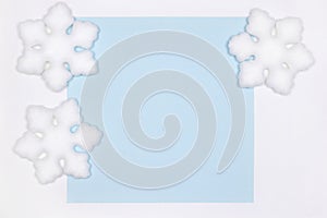 White snowflake decorations on blue card flat lay. Copy space. Simple winter background