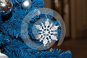 White snowflake and silver balls on a blue Christmas tree