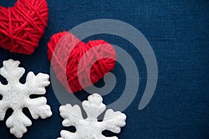 White snowflakes and red wool hearts on blue canvas background. Merry christmas card.