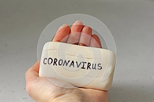 White soap lies in a female hand. Word coronavirus is written on soap. Concept of hand washing, hygiene, for prevention of