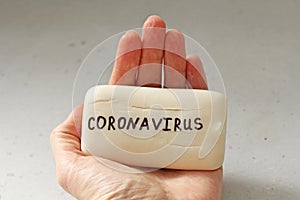 White soap lies in a female hand. Word coronavirus is written on soap. Concept of hand washing, hygiene, for prevention of