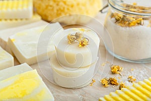 White soap round bars with herbs dry marigold flowers. Spa bathroom products aroma salt, many natural artisan soaps on marble