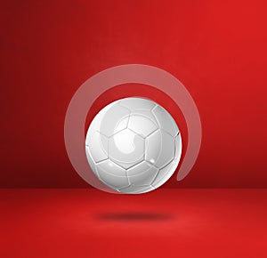 White soccer ball on a red studio background