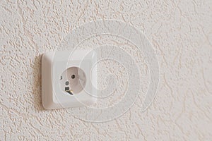 A white socket on the wall. Electricity equipment in interior