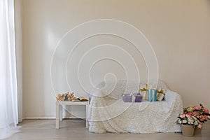 white sofa with gifts and green plant coffee table with flowers in bright interior room