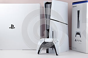 The white Sony PlayStation 5 and controller on the white table.