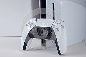 The white Sony PlayStation 5 and controller on the white table.