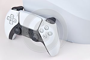 The white Sony PlayStation 5 and controller on the white table.