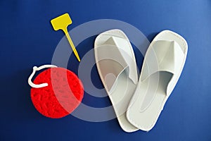 White Spa Slippers with New Red Sponge and Empty Yellow Labels  on Blue Background