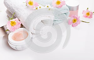 White spa towel with wild roses and cream on white background