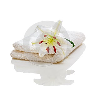 White spa towels with lily on white and reflection