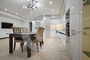 White spacious kitchen interior with dining room table and chairs